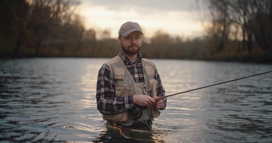 The man smiles while fly fishing