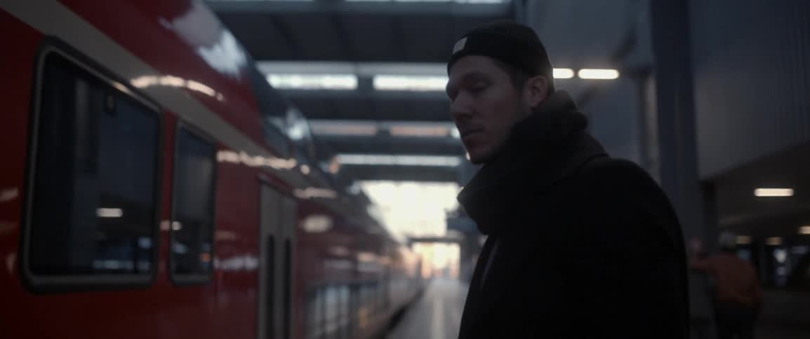 A man stands waiting for a train