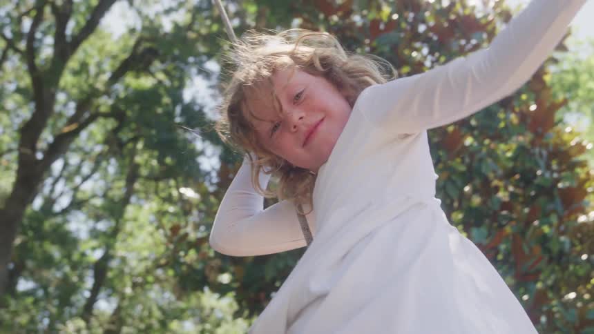 Girl swings while hanging from a rope outdoors