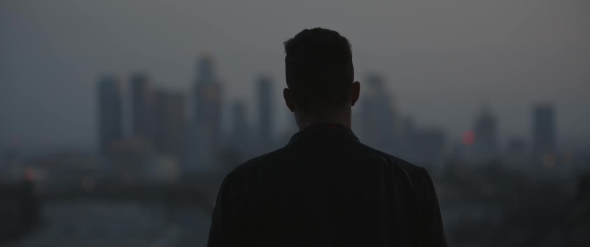 A man looks at city skyscrapers at sunset