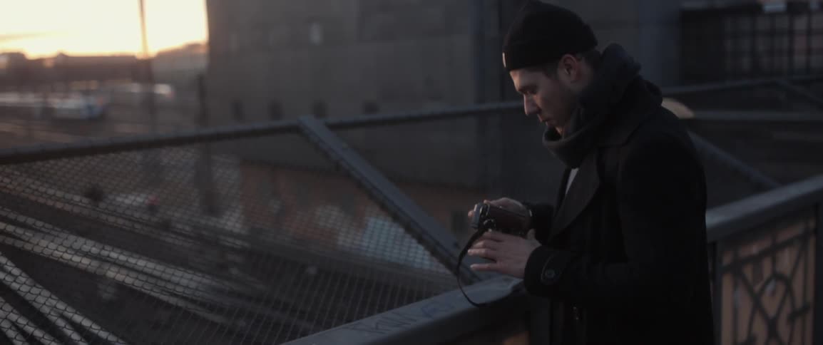 A man looks at his camera on a rooftop