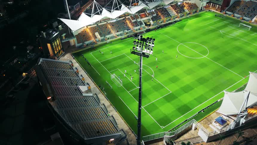 Soccer players run around the stadium field at night