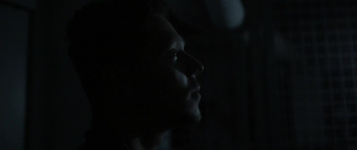 A man stares off in a dark area