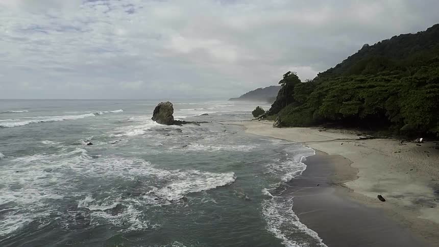 Waves crash against the shore on a cloudy day