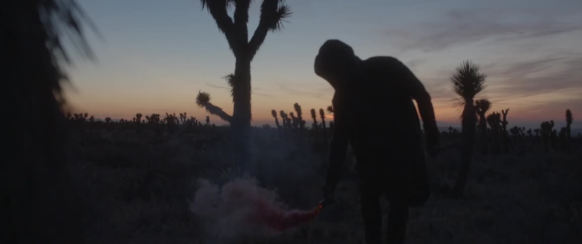 A person in a hooded jacket waves a flare