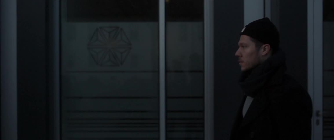 A man walking by the front of a building at night