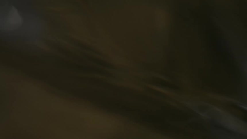 A handheld closeup shot observes the surface of dark rippling water highlighting the shifting textures and occasional bright reflections