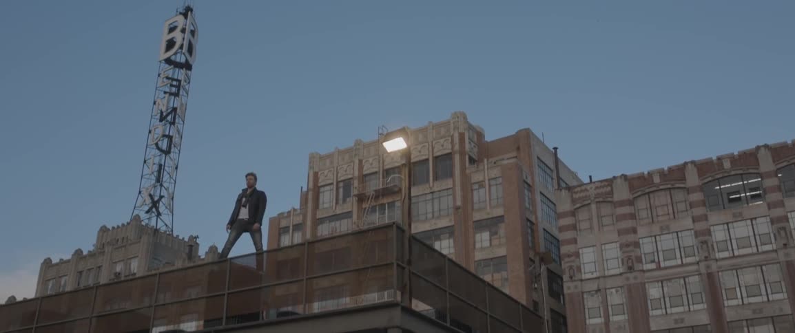 A man stands on a city rooftop