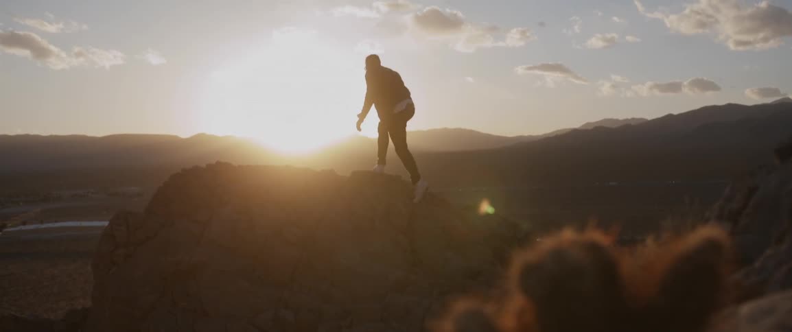 A man climbs up over some rocks