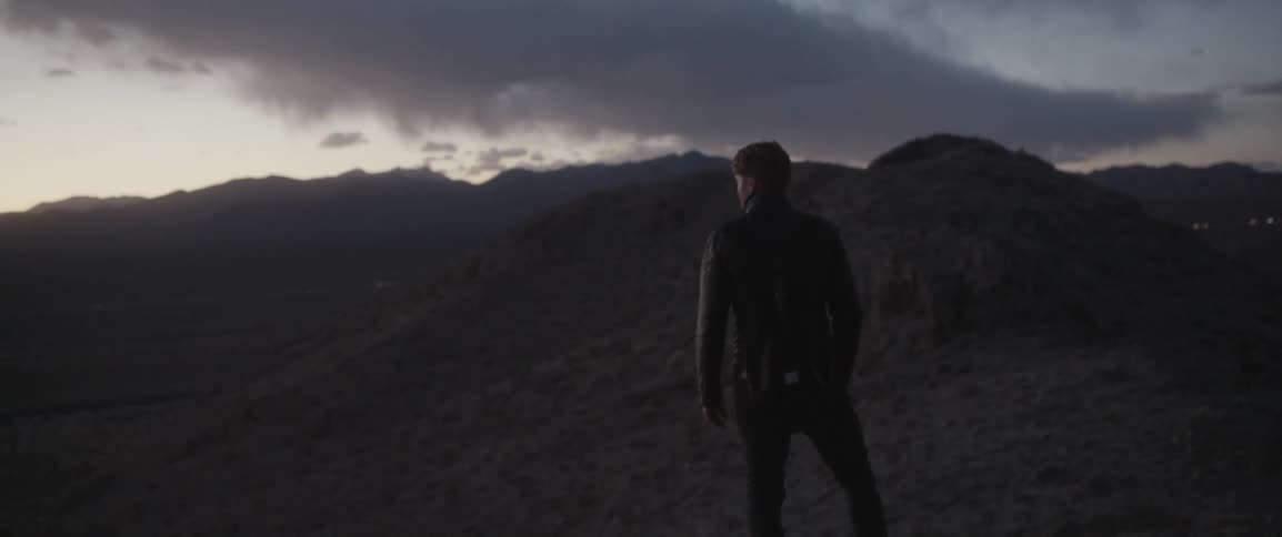 Man standing and looking out at surroundings in wilderness at dusk