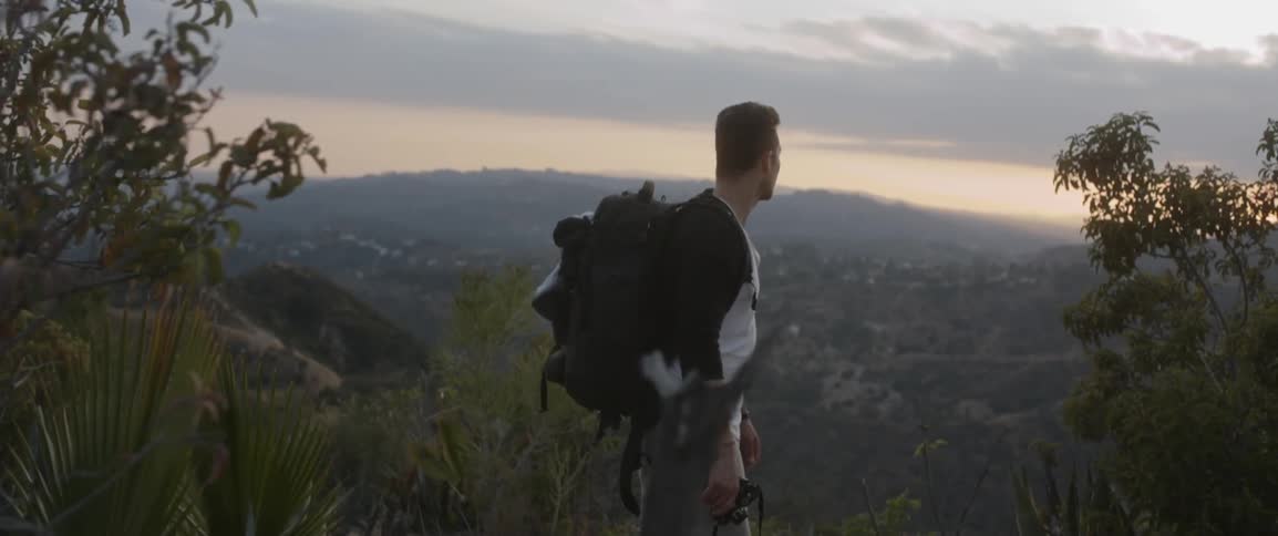 Man wearing a backpack looks out at hills