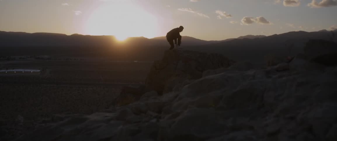 Man climbs up rocky hills on a sunny day