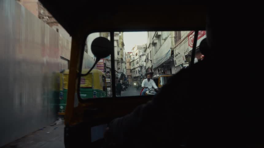 A man drives a tricycle along a busy street at midday