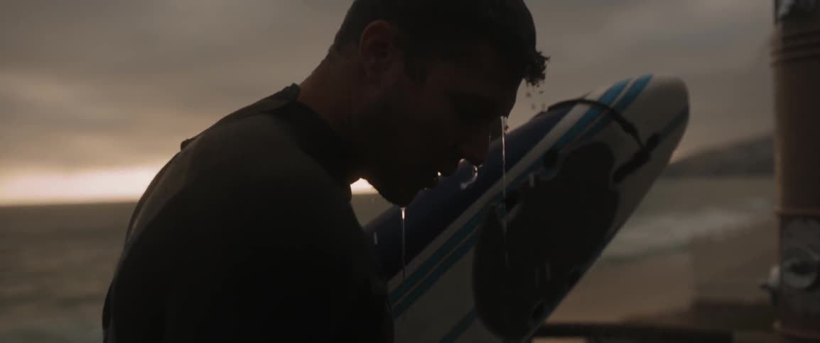 Dripping wet man holds a surfboard