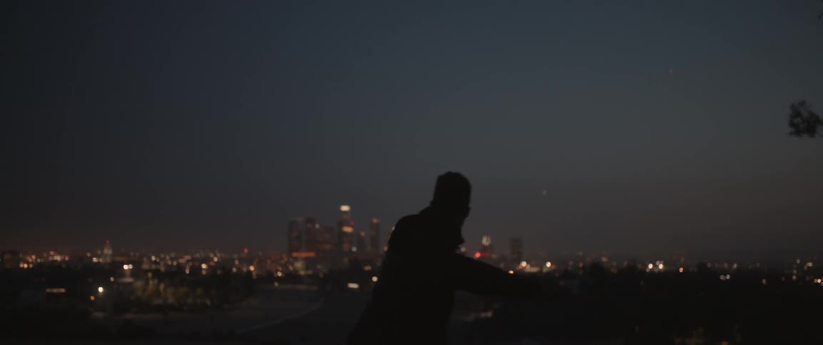 Silhouette of a man jumping at night with a city in the background