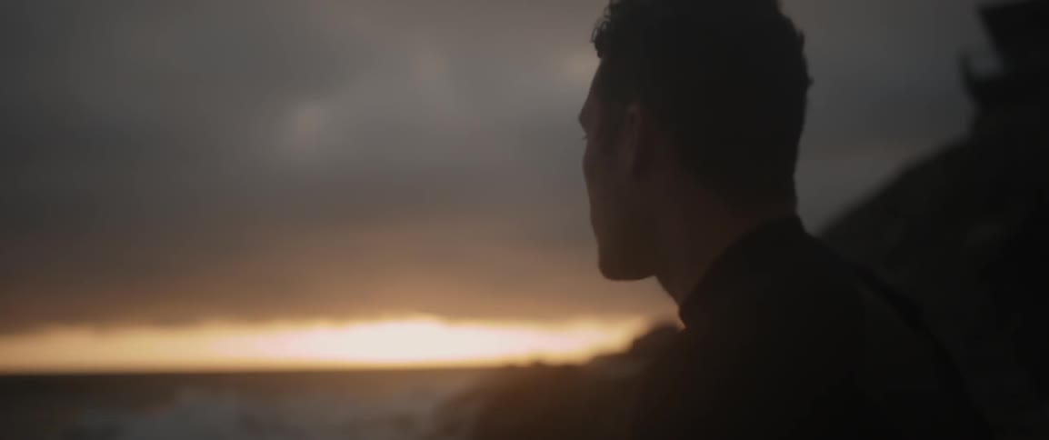 A man stands on a beach at sunset
