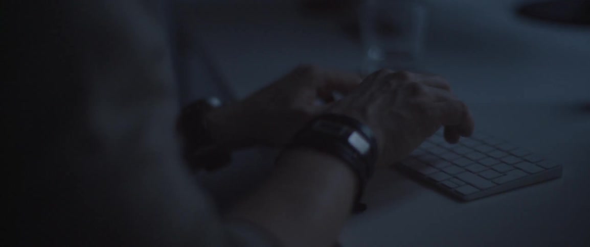 A man is typing in a dark room