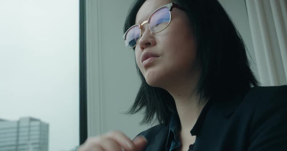 A woman stands in an office while looking out the window