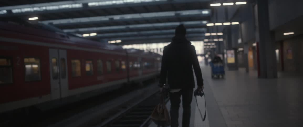 A man walks past a train station carrying a camera