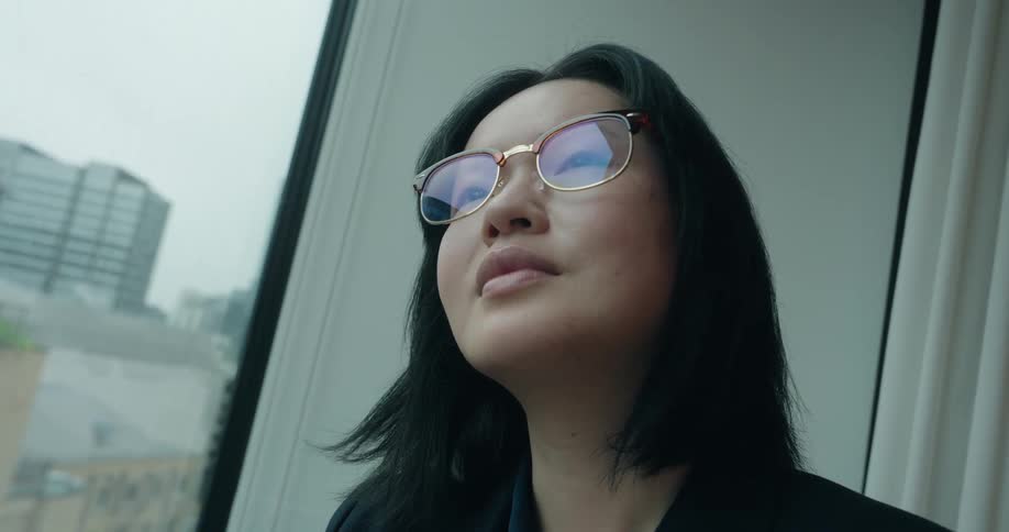 Woman with crossed arms looks out window
