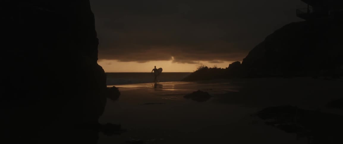 A man runs with a surfboard by the water