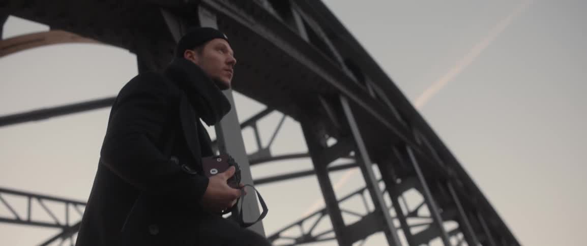 A man is holding a camera on a bridge