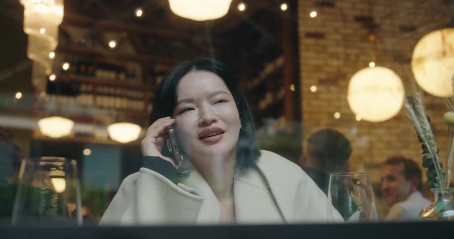 Woman on the phone inside a restaurant seen through the window