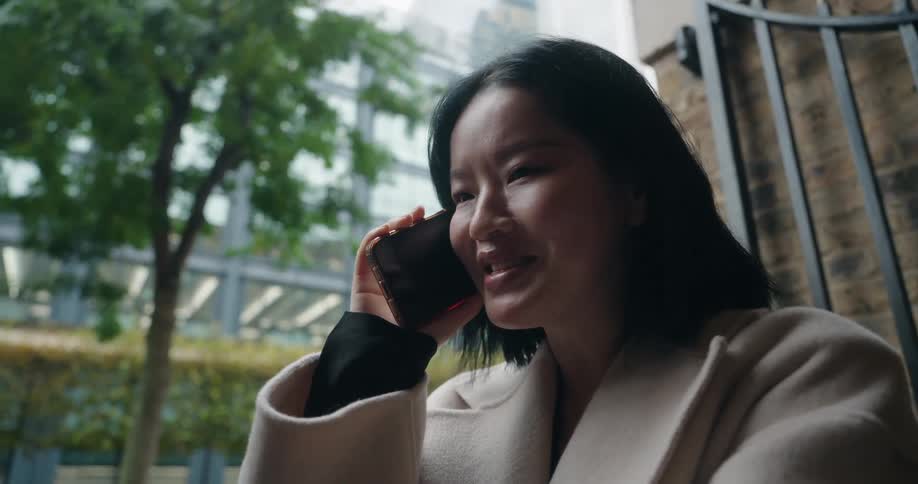 Smiling woman talks on the phone while outdoors