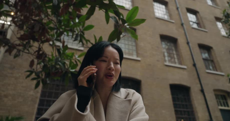 The woman talks on the phone outside the building