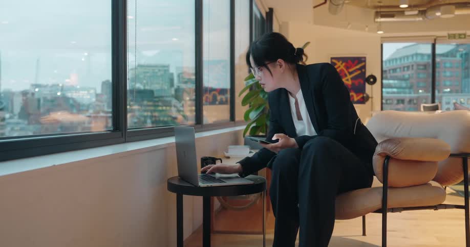 The office worker uses her cell and laptop at the same time