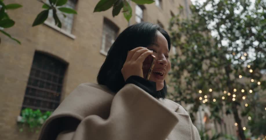 Woman standing outside in front of an apartment buildling as she talks on her phone
