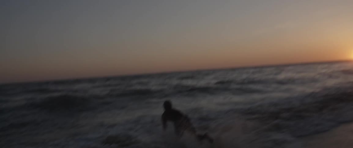 A man runs into the ocean with a surfboard