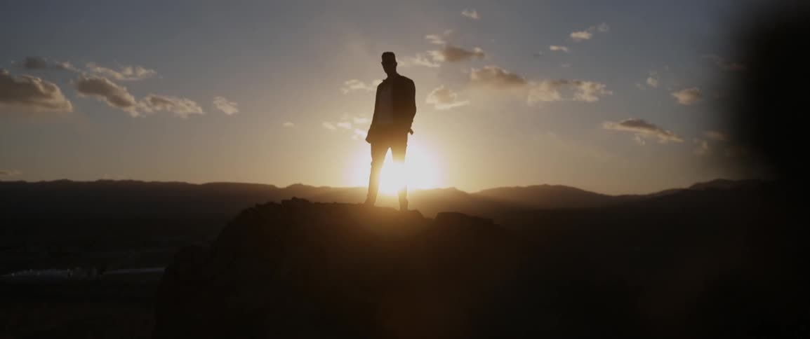 A man stands on some rocks at dawn