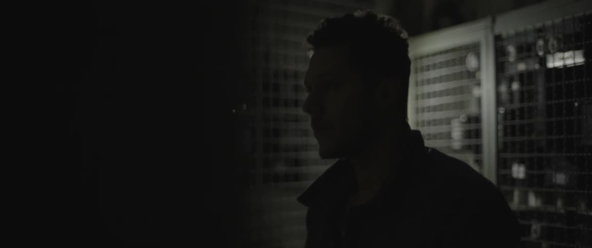 A man stands in a dark room looking up