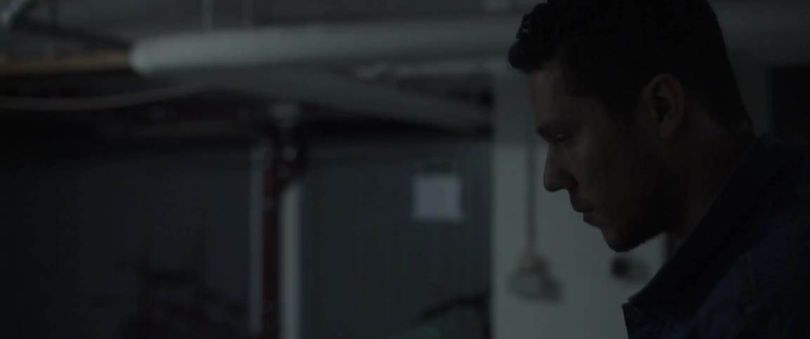A short haired man walks through a dim room