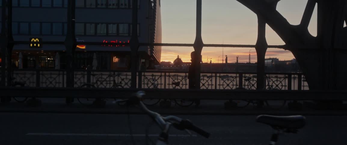 A man walks on a bridge at sunset