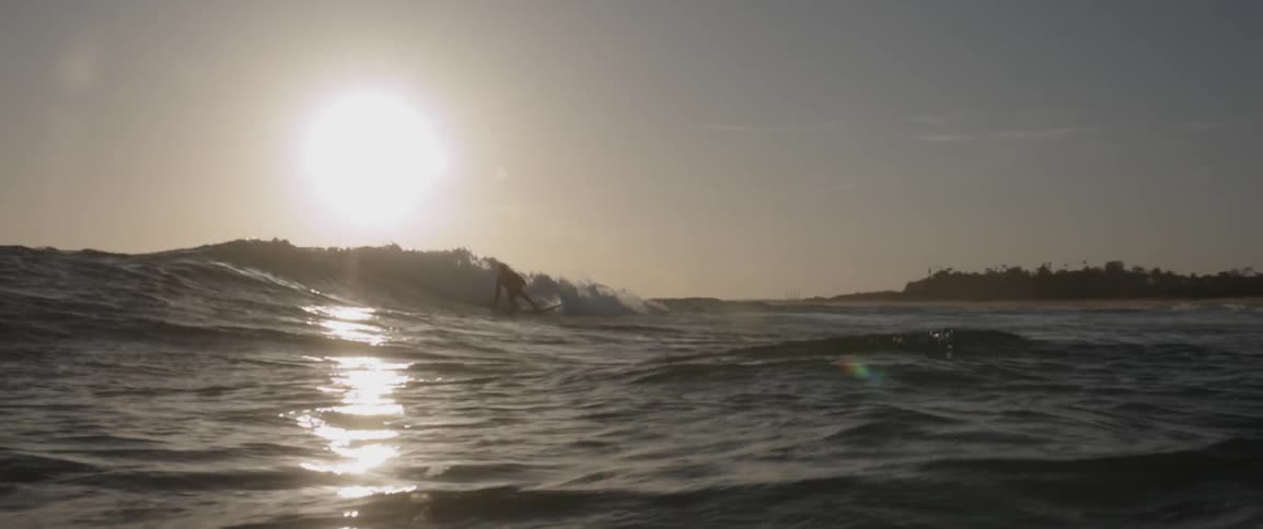A man is surfing at sunset