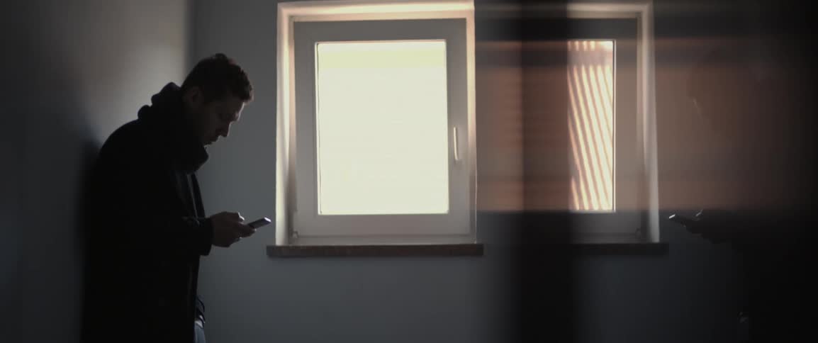 A man is using his phone near a window