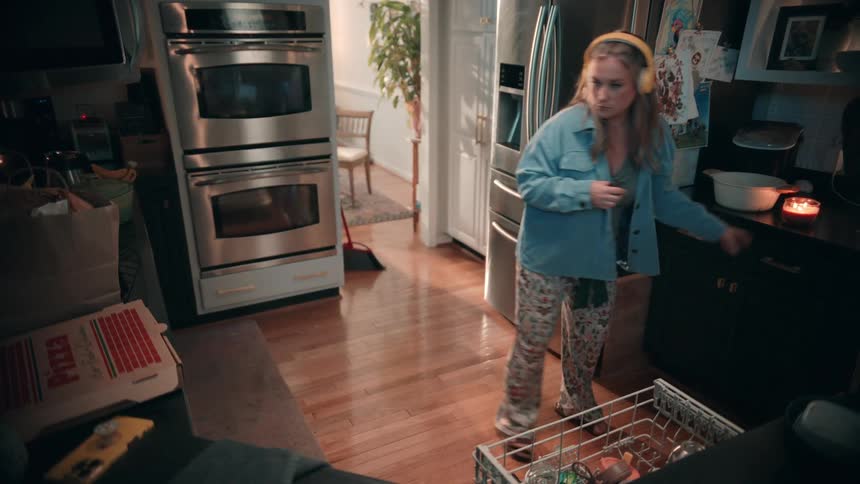 Woman wearing headphones lights a candle and interacts with a microwave