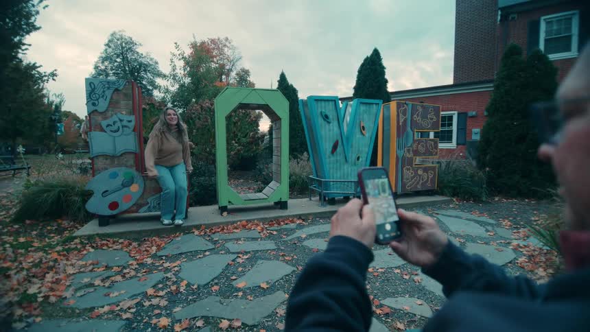 The man takes a picture of a woman with a cell phone