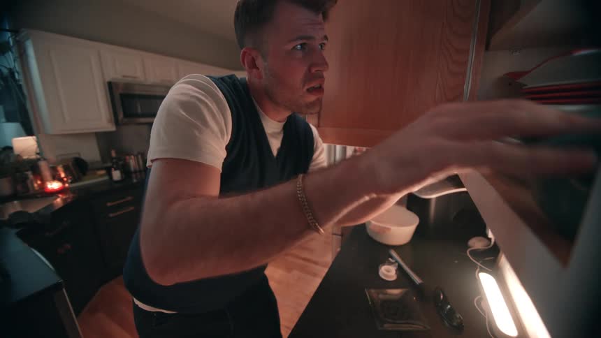 Man organizing items in a kitchen cabinet