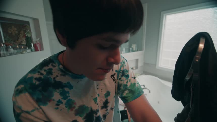 Teenager boy brushing his teeth in a bathroom indoors during day time