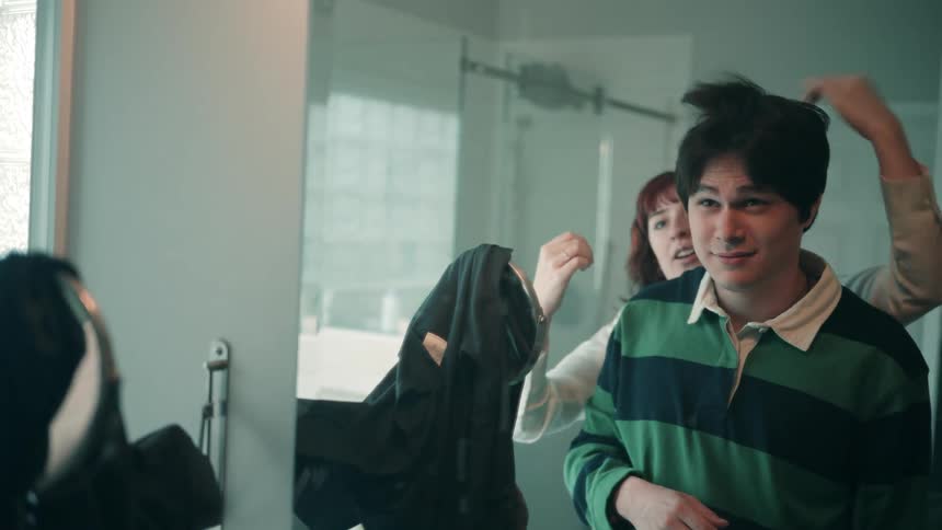 Person fixing someones hair in front of the bathroom mirror
