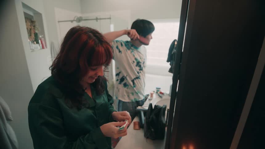 A happy couple getting ready together near mirror in a bright modern bathroom