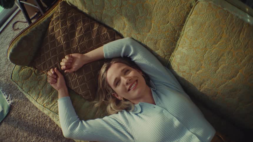 A woman laying on a couch and laughing