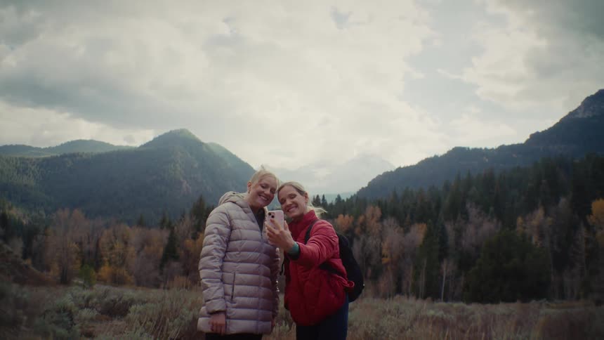 Two women take a selfie in front of the mountains