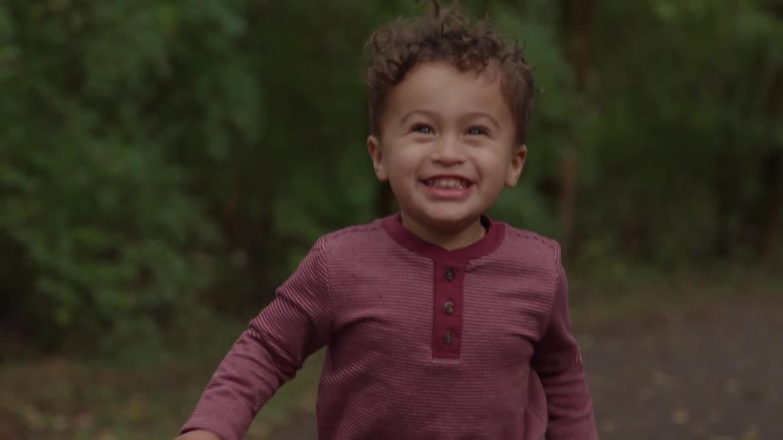 Child running outdoors wearing a red striped shirt
