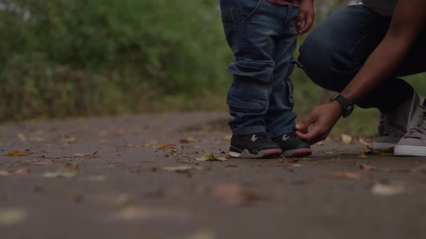 A person tying shoes on a child