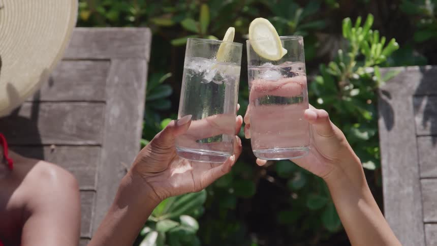 Two women clanking glasses outdoors