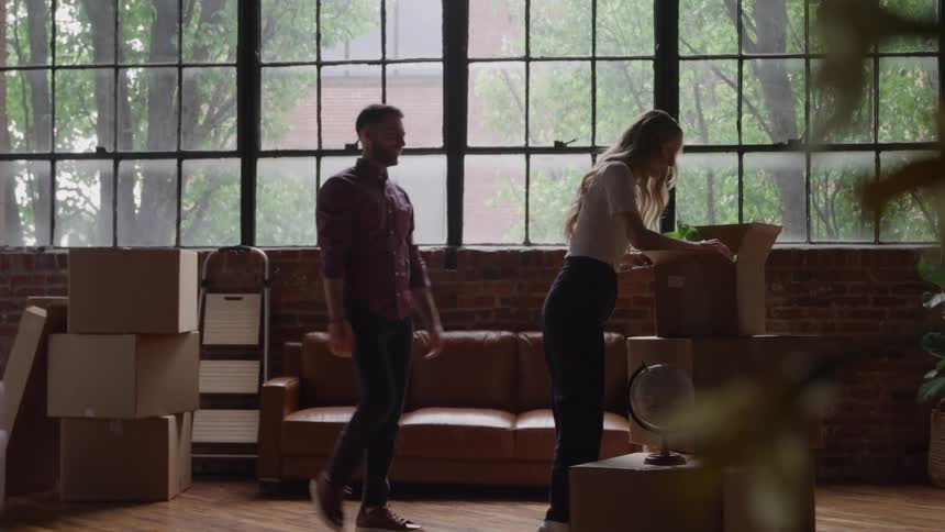 The man and woman unpacking boxes begin dancing